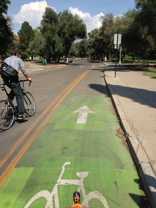 The entrance to the contraflow bike lane is green and has a bike and arrow legend. The rider on the left is merging from the left. 