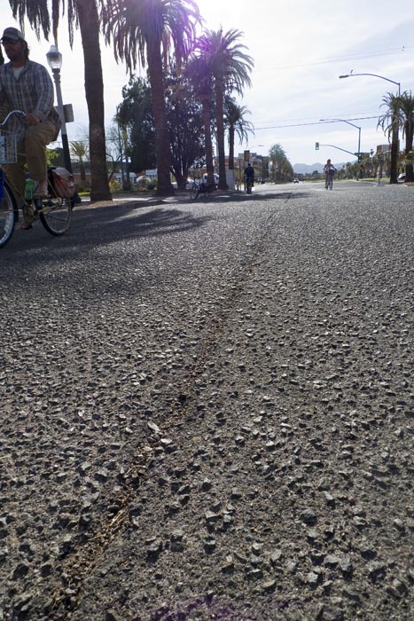 A cyclist rides east on Third Street avoding the cracks.