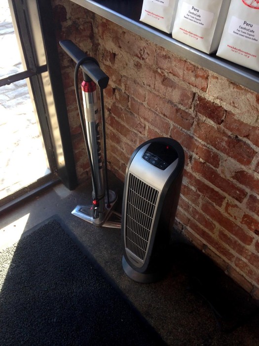 A bike pump sits inside the coffee shop door. 