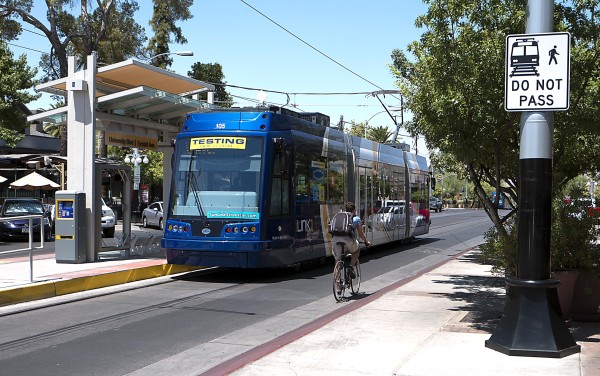 A cyclist passes the streetcar on the right at a stop.